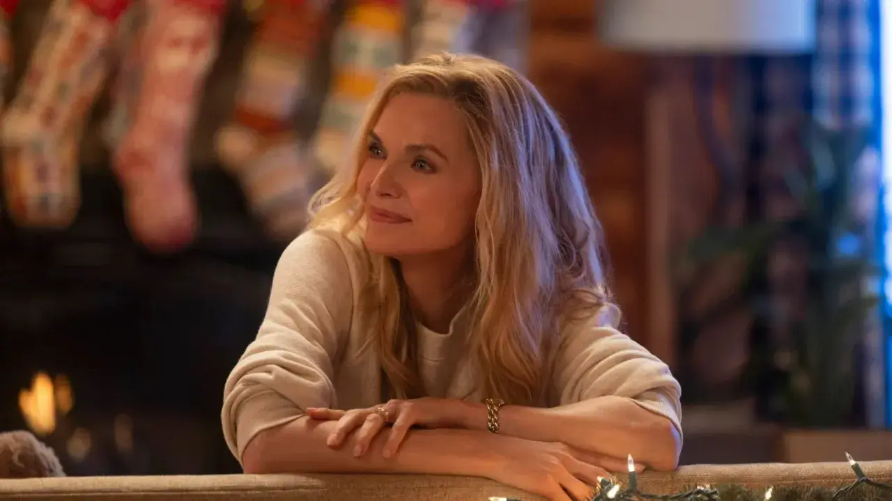 Michelle Pfeiffer in un film natalizio, con calze appese al camino e luci scintillanti.