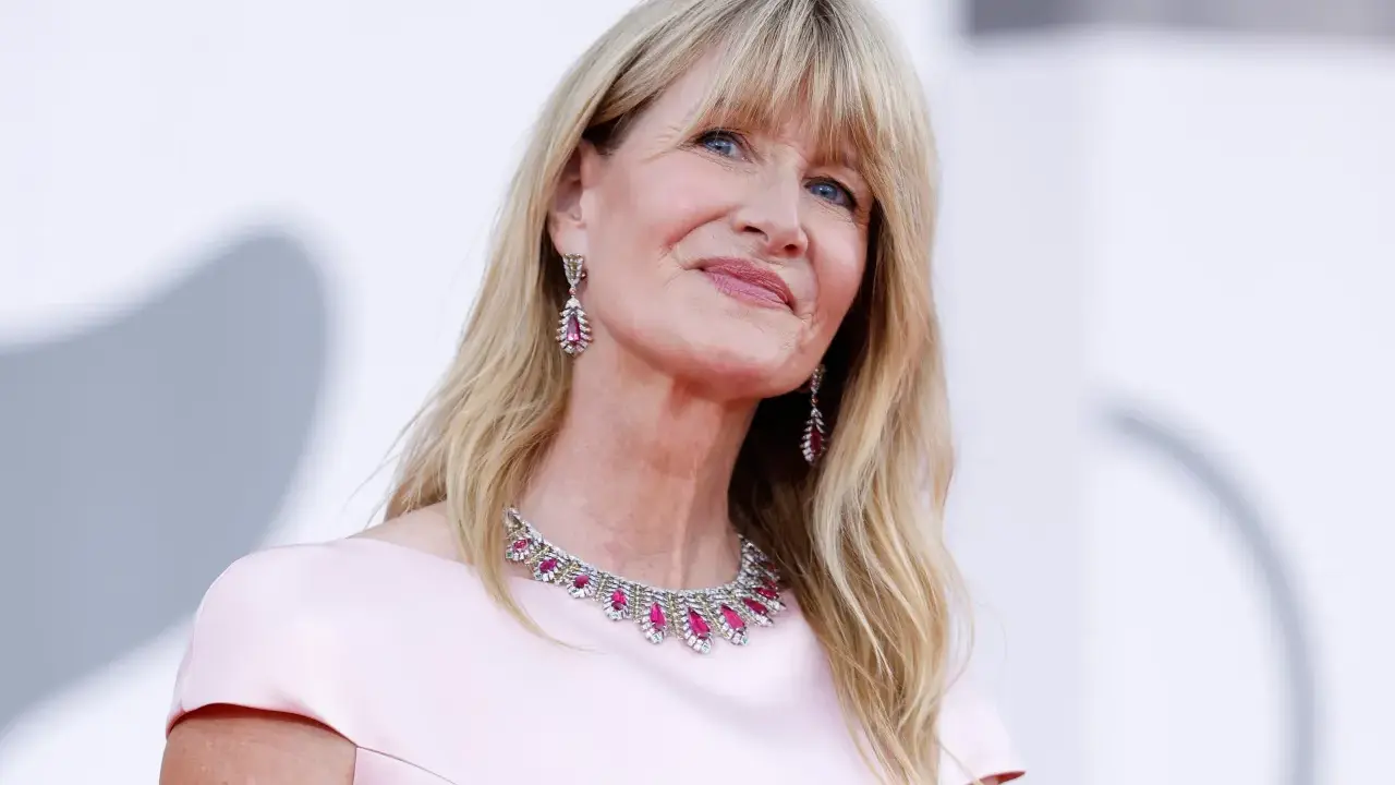 L'attrice bionda americana Laura Dern sorride con un abito rosa e gioielli scintillanti.