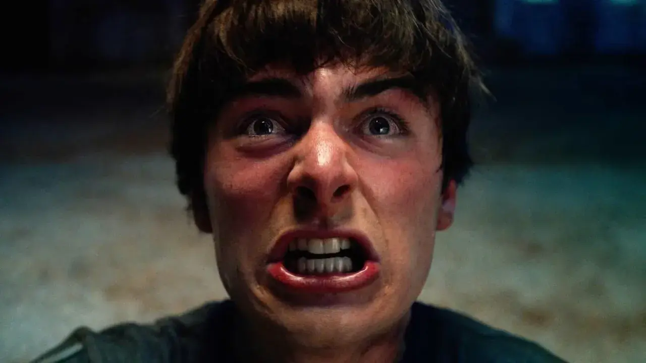 Un primo piano terrificante di un giovane con gli occhi spalancati e la bocca aperta, pronto ad affrontare le minacce di Stranger Things 5.