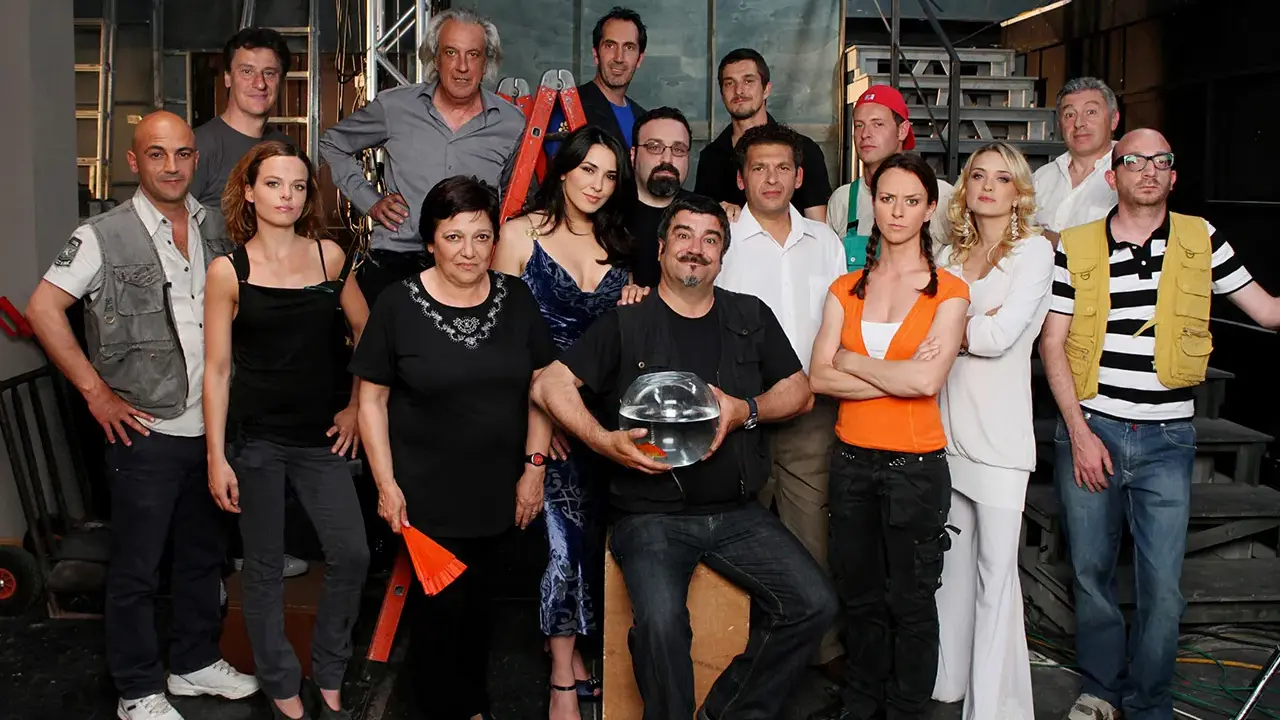 Il cast di Boris posa per una foto di gruppo, con un uomo che tiene una boccia con un pesce rosso.