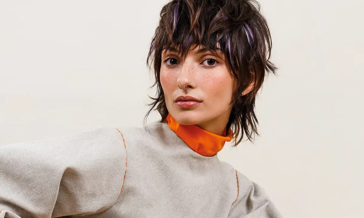 Modella con sbarazzini tagli capelli corti spettinati, ciocche viola e un look audace.
