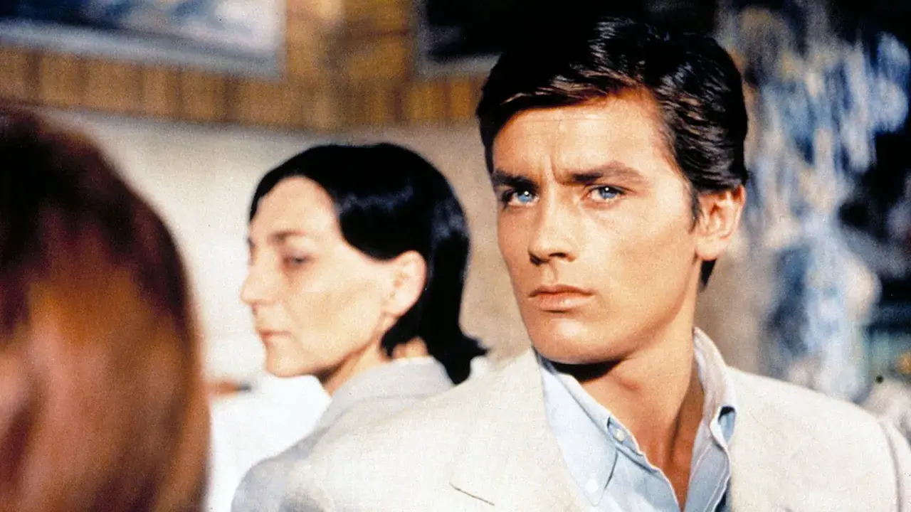 Alain Delon, icona di stile, in una scena che evoca i suoi film più belli. Sguardo intenso, fascino intramontabile.