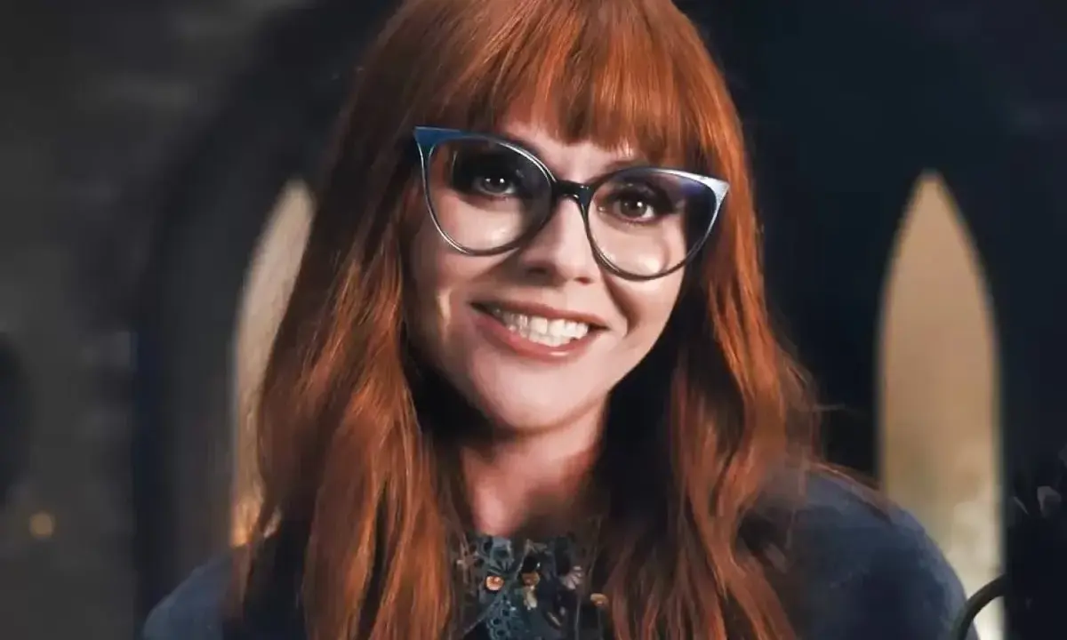 Christina Ricci, chi ha interpretato Mercoledì Addams, sorride con occhiali cat-eye e capelli rossi.