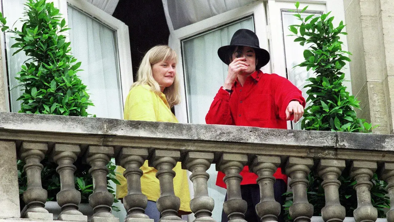 Michael Jackson con un cappello nero e una camicia rossa, accanto a una donna bionda. Forse la sua moglie?