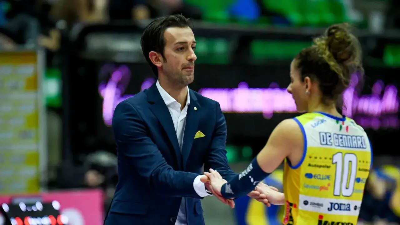 Santarelli de Gennaro, allenatore, stringe la mano a una giocatrice di pallavolo con la maglia numero 10.