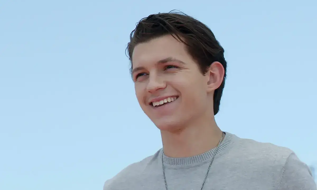 Tom Holland sorride con un maglione grigio. Chissà quanti anni ha Tom Holland?
