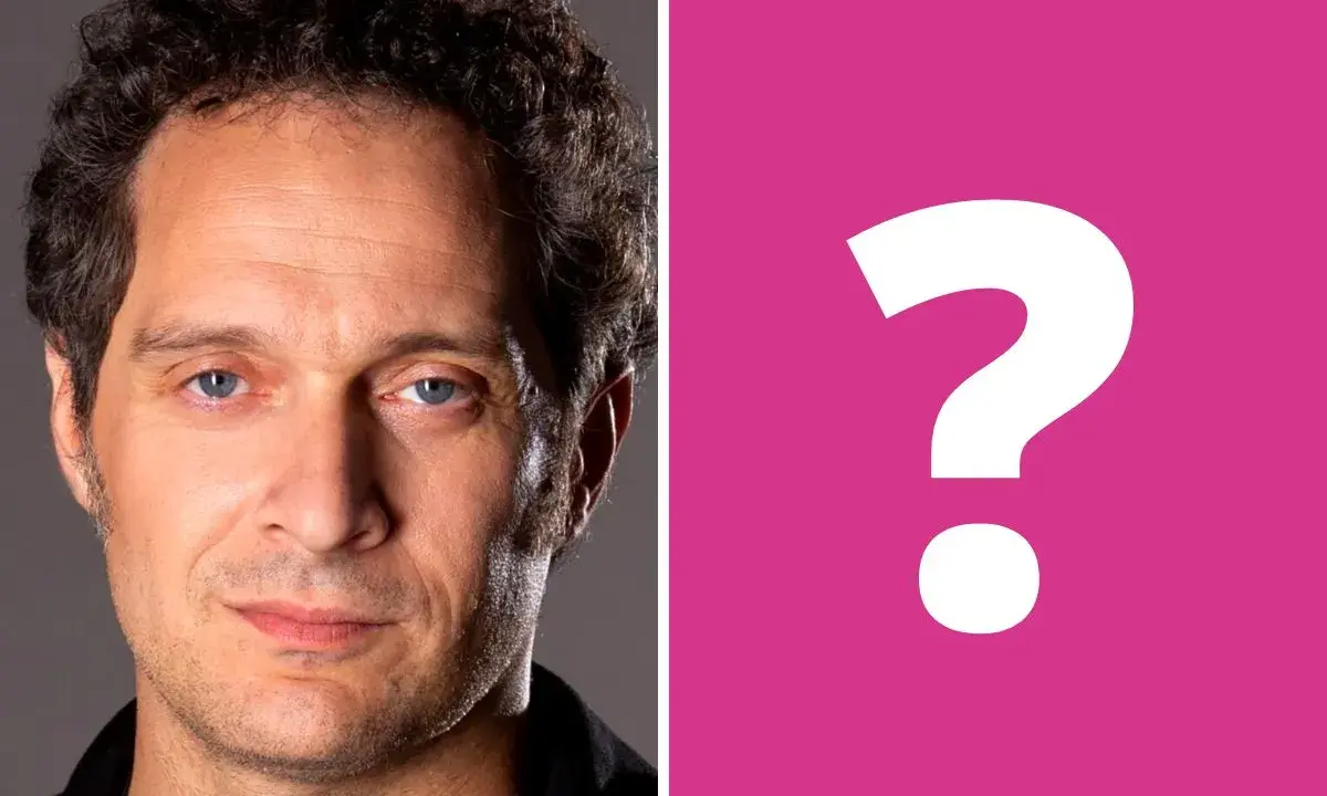 Primo piano di Claudio Santamaria, con un punto interrogativo rosa a destra. Forse si cerca la sua ex moglie?