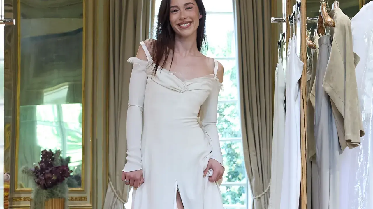 Un abito da sposa bianco, simile a quello di Michelle Hunziker con Eros Ramazzotti, indossato da una giovane donna sorridente in una stanza elegante.