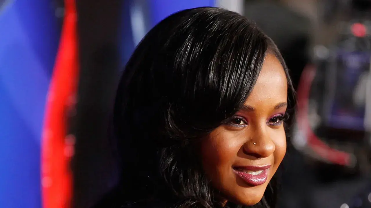 La figlia di Whitney Houston, Bobbi Kristina Brown, sorride con un trucco viola e capelli scuri.