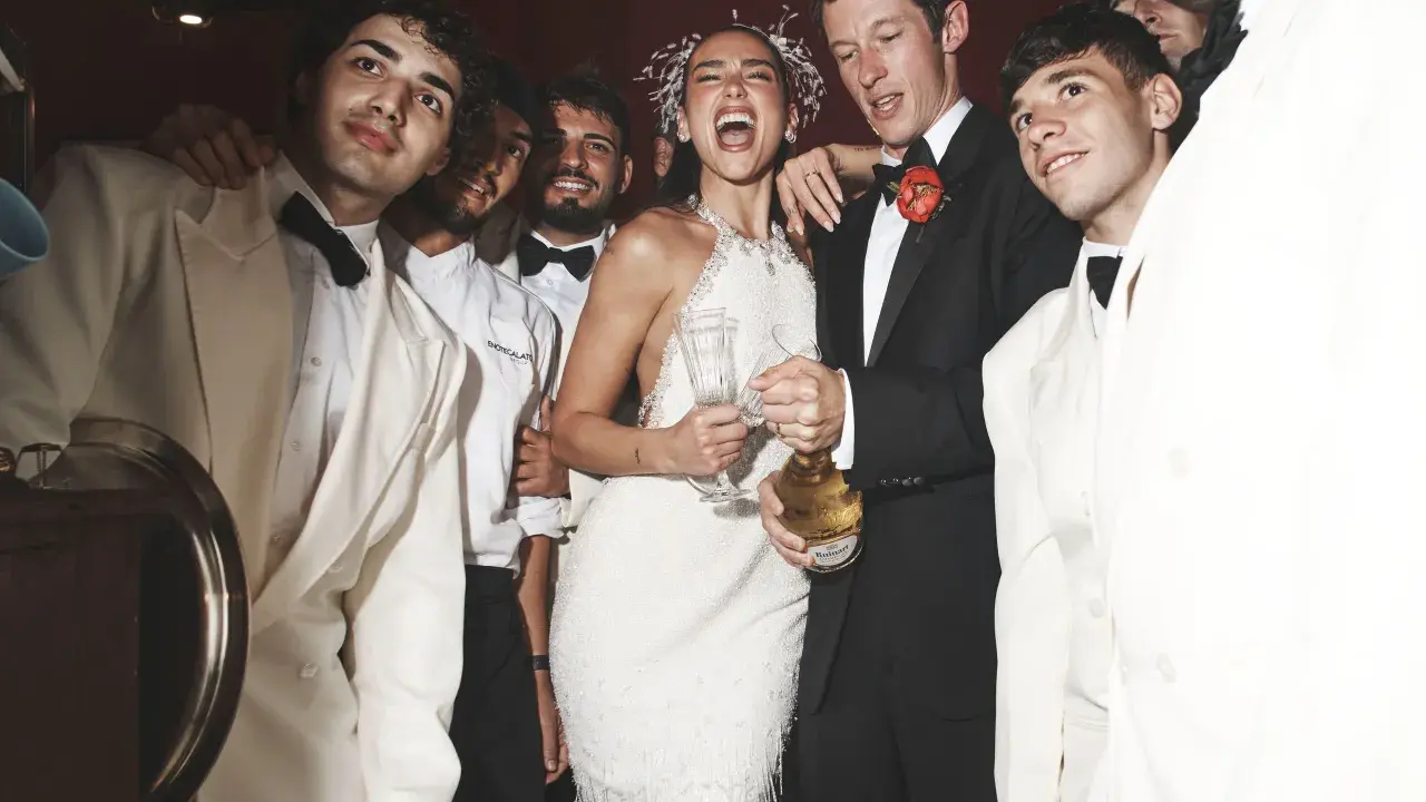 Dua Lipa festeggia il suo matrimonio con amici in abiti eleganti, champagne alla mano.