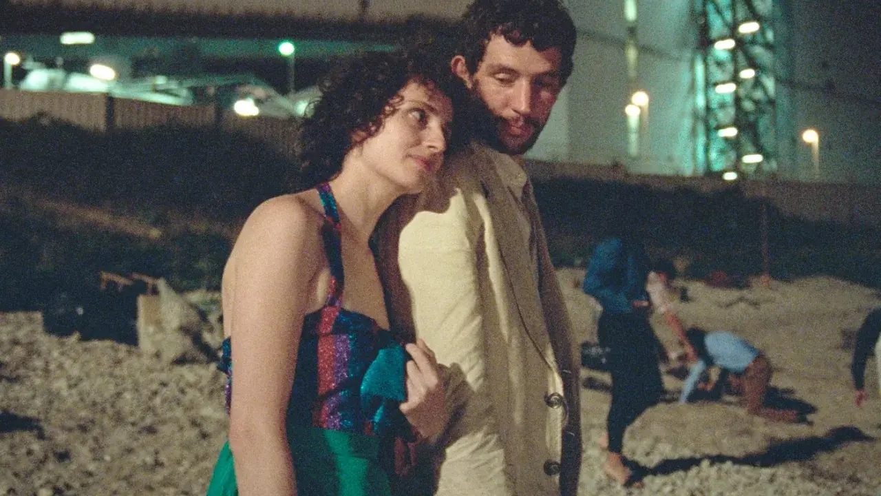 Il cast de "La Chimera" in un momento intimo, con altre figure sfocate sullo sfondo notturno.