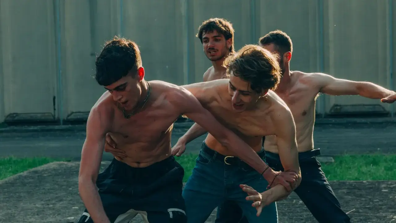 Ragazzi a torso nudo si allenano in un cortile, un momento intenso dalla **prisma serie tv**.