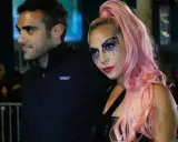 Lady Gaga con il suo fidanzato, Christian Carino, durante un evento. Lei indossa un trucco scintillante e capelli rosa.