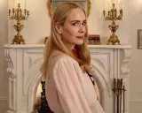 Sarah Paulson in un'ambientazione vittoriana, forse per American Horror Story 13. Un camino ornato e candelabri dorati creano un'atmosfera inquietante.