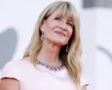 L'attrice bionda americana Laura Dern sorride con un abito rosa e gioielli scintillanti.