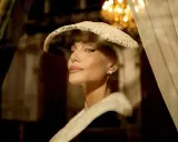 Angelina Jolie nei panni di Maria Callas, con un cappello di pizzo e una pelliccia, evoca l'eleganza di un'epoca passata.