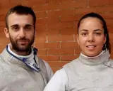 Alice Volpi con il suo fidanzato, entrambi schermidori, posano sorridenti davanti a un muro di mattoni.