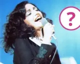 Cantante con microfono, forse un momento della sua **mia martini gravidanza**? Un punto interrogativo rosa campeggia a destra.