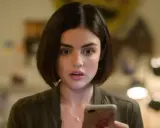 Lucy Hale, protagonista di film e programmi TV, guarda sorpresa il suo telefono.