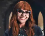 Christina Ricci, chi ha interpretato Mercoledì Addams, sorride con occhiali cat-eye e capelli rossi.
