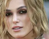 Primo piano di una donna con taglio butterfly capelli corti biondi, trucco occhi intenso e labbra rosa.