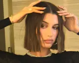 Modello con capelli castani, lisci e pochi, che sfoggia un taglio a caschetto. Indossa gioielli d'oro e un abito nero.