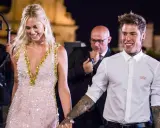 Fedez e Chiara sorridono, un momento speciale che ricorda la loro canzone. Lei indossa un abito scintillante, lui una camicia bianca.