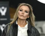 Kate Moss oggi, con un look audace e un trucco marcato, sfila con un giubbotto di pelle e una camicia bianca.