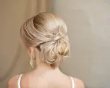Chignon basso cerimonia con capelli biondi intrecciati, un'acconciatura elegante e raffinata per un'occasione speciale.