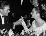 Richard Burton offre un fiore a Elizabeth Taylor, suo coniuge, in un momento di tenerezza tra fiori.