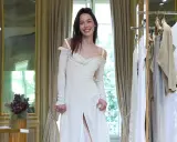 Un abito da sposa bianco, simile a quello di Michelle Hunziker con Eros Ramazzotti, indossato da una giovane donna sorridente in una stanza elegante.