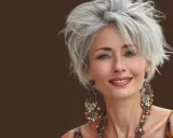 Donna sorridente con over 50 capelli corti mossi spettinati, orecchini etnici e un top colorato.