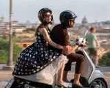 Emily in Paris 4: Emily e Gabriel sfrecciano su uno scooter a Roma, con la città sullo sfondo.