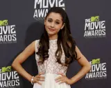 Ariana Grande, con la sua tipica acconciatura, posa sul red carpet degli MTV Movie Awards. La sua ariana grande altezza è accentuata dal vestito floreale.