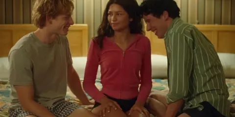 Zendaya in un momento intimo tra i suoi film e programmi TV, circondata da due uomini sorridenti.