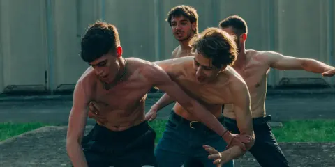 Ragazzi a torso nudo si allenano in un cortile, un momento intenso dalla **prisma serie tv**.