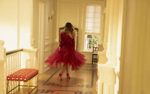 E così, con un vortice di tulle rosso, una donna balla in un corridoio luminoso.