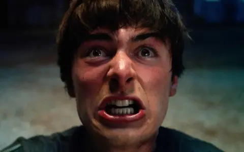 Un primo piano terrificante di un giovane con gli occhi spalancati e la bocca aperta, pronto ad affrontare le minacce di Stranger Things 5.