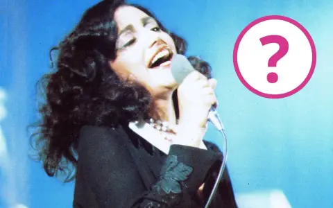 Cantante con microfono, forse un momento della sua **mia martini gravidanza**? Un punto interrogativo rosa campeggia a destra.