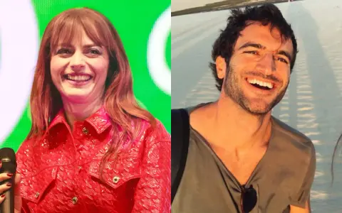 Annalisa e Francesco Muglia sorridono felici, uno sul palco con giacca rossa, l'altro in spiaggia.