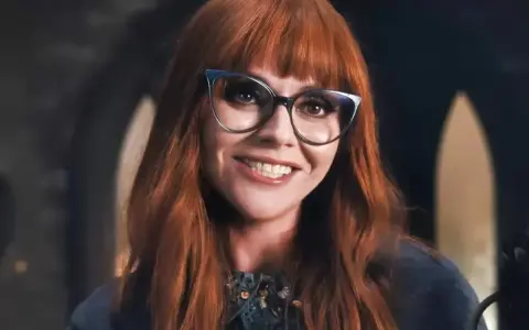 Christina Ricci, chi ha interpretato Mercoledì Addams, sorride con occhiali cat-eye e capelli rossi.