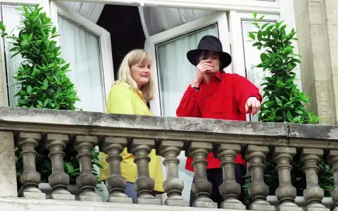 Michael Jackson con un cappello nero e una camicia rossa, accanto a una donna bionda. Forse la sua moglie?