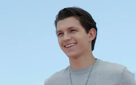 Tom Holland sorride con un maglione grigio. Chissà quanti anni ha Tom Holland?