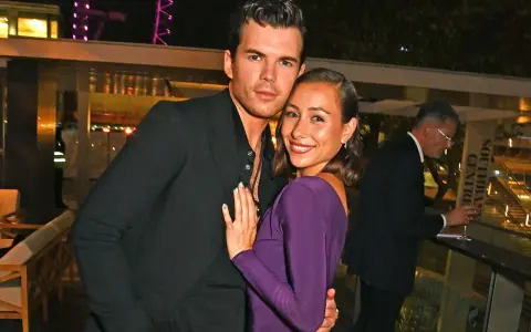 Luke Newton e la sua fidanzata, sorridenti e abbracciati, in un evento serale.
