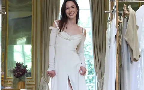 Un abito da sposa bianco, simile a quello di Michelle Hunziker con Eros Ramazzotti, indossato da una giovane donna sorridente in una stanza elegante.