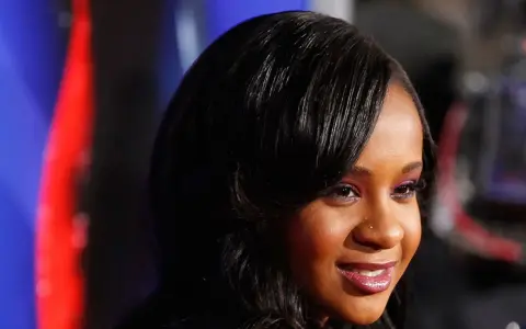 La figlia di Whitney Houston, Bobbi Kristina Brown, sorride con un trucco viola e capelli scuri.