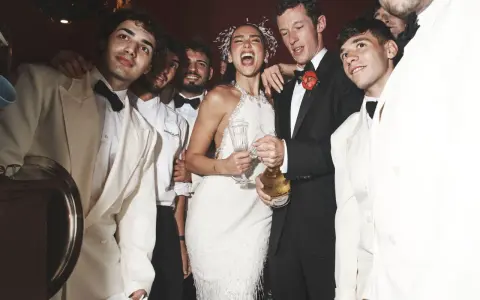Dua Lipa festeggia il suo matrimonio con amici in abiti eleganti, champagne alla mano.