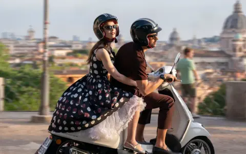 Emily in Paris 4: Emily e Gabriel sfrecciano su uno scooter a Roma, con la città sullo sfondo.