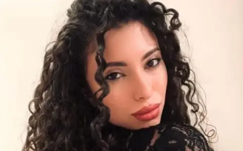 La nuova fidanzata di Raimondo Todaro, con lunghi capelli ricci e labbra rosse, posa con un abito di pizzo nero.