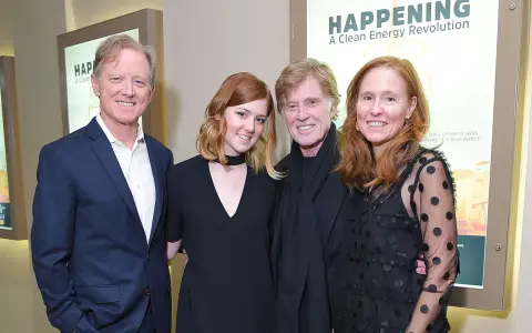 Robert Redford con i suoi figli, un momento di famiglia davanti a un poster su un'energia pulita.